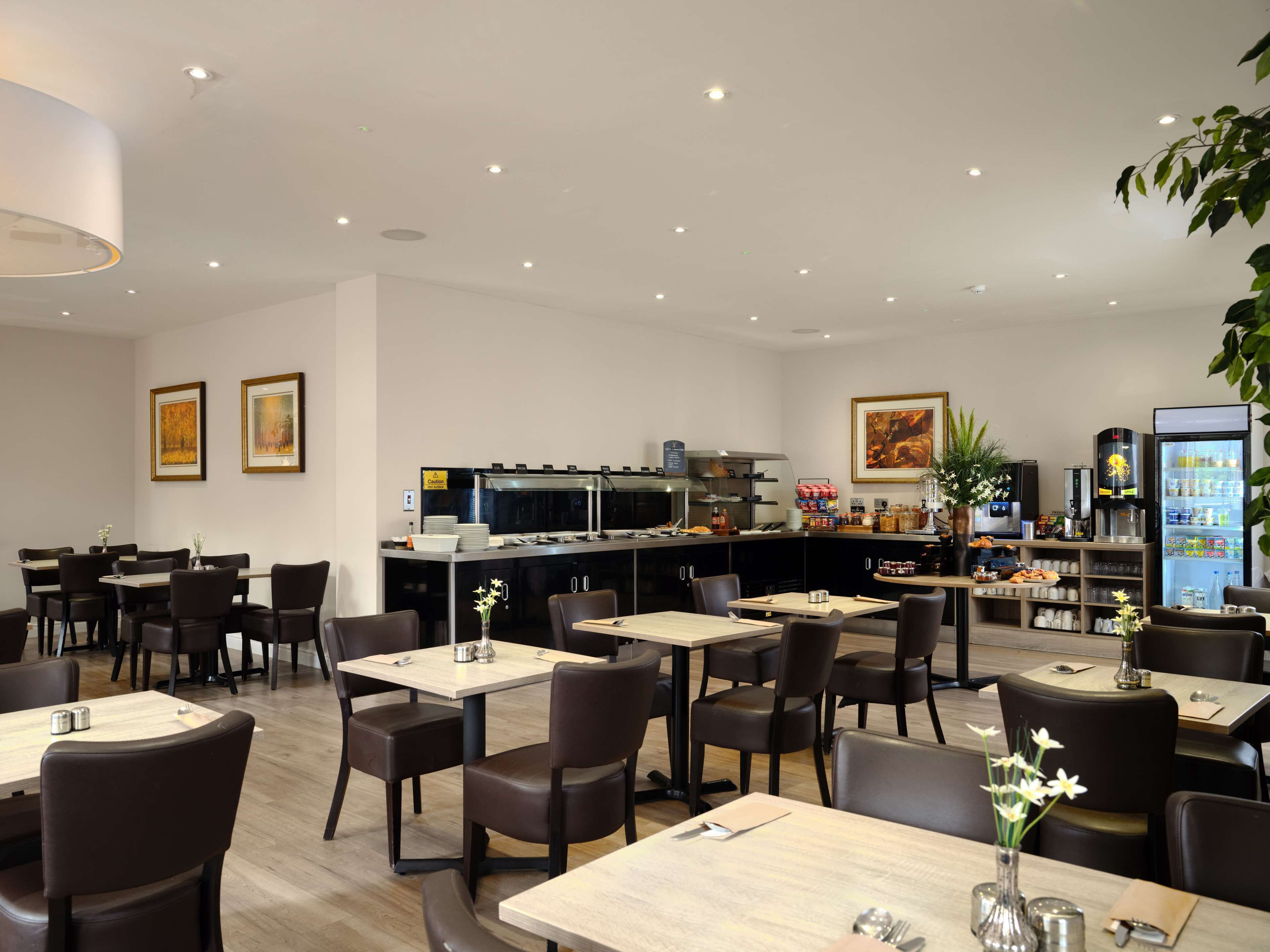 A modern restaurant with a bar area, dining tables, and chairs.