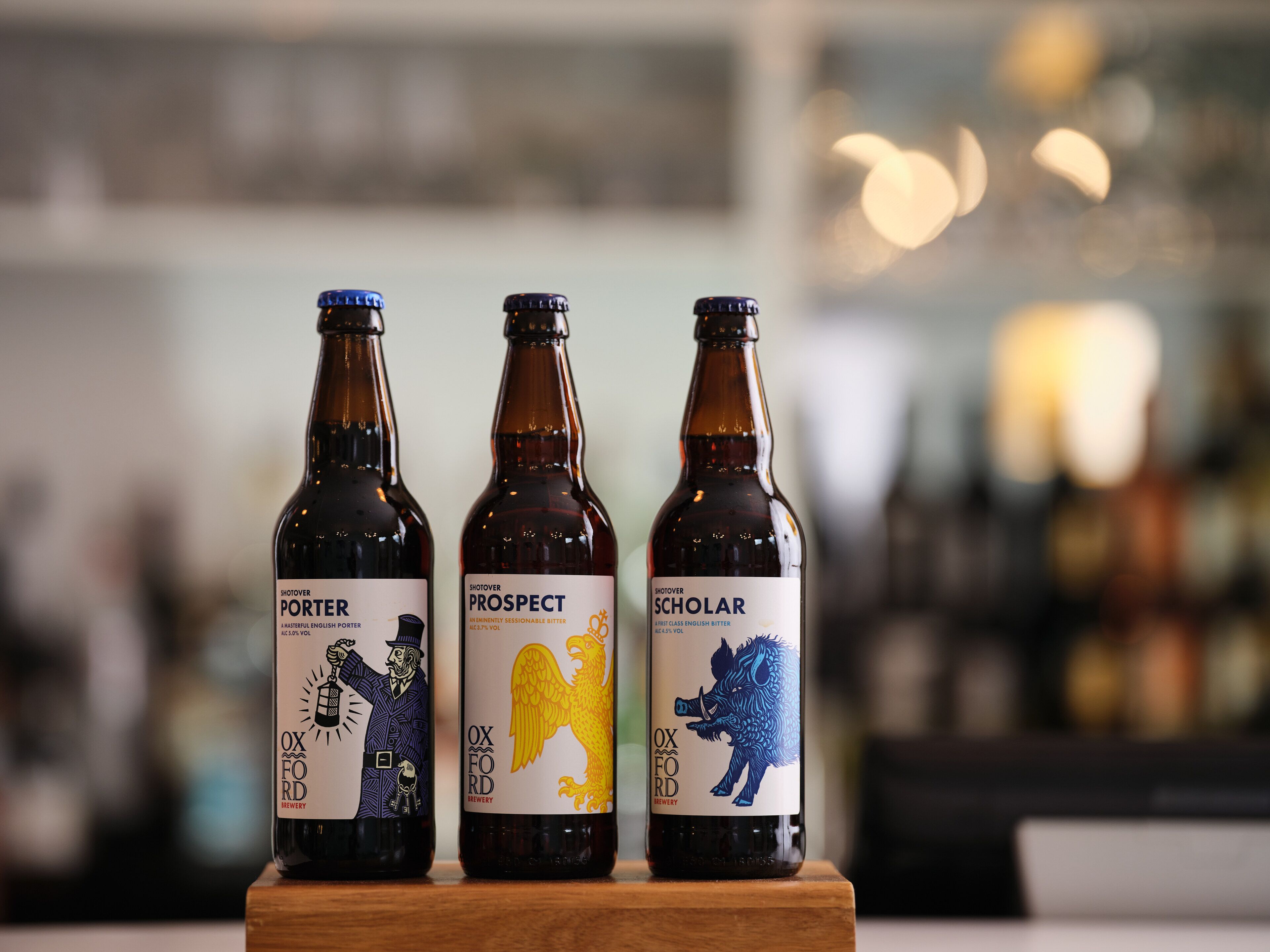 Three bottles of beer with distinct labels on a wooden surface.