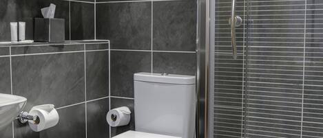 Un baño moderno con inodoro, lavamanos y ducha con mampara de vidrio.