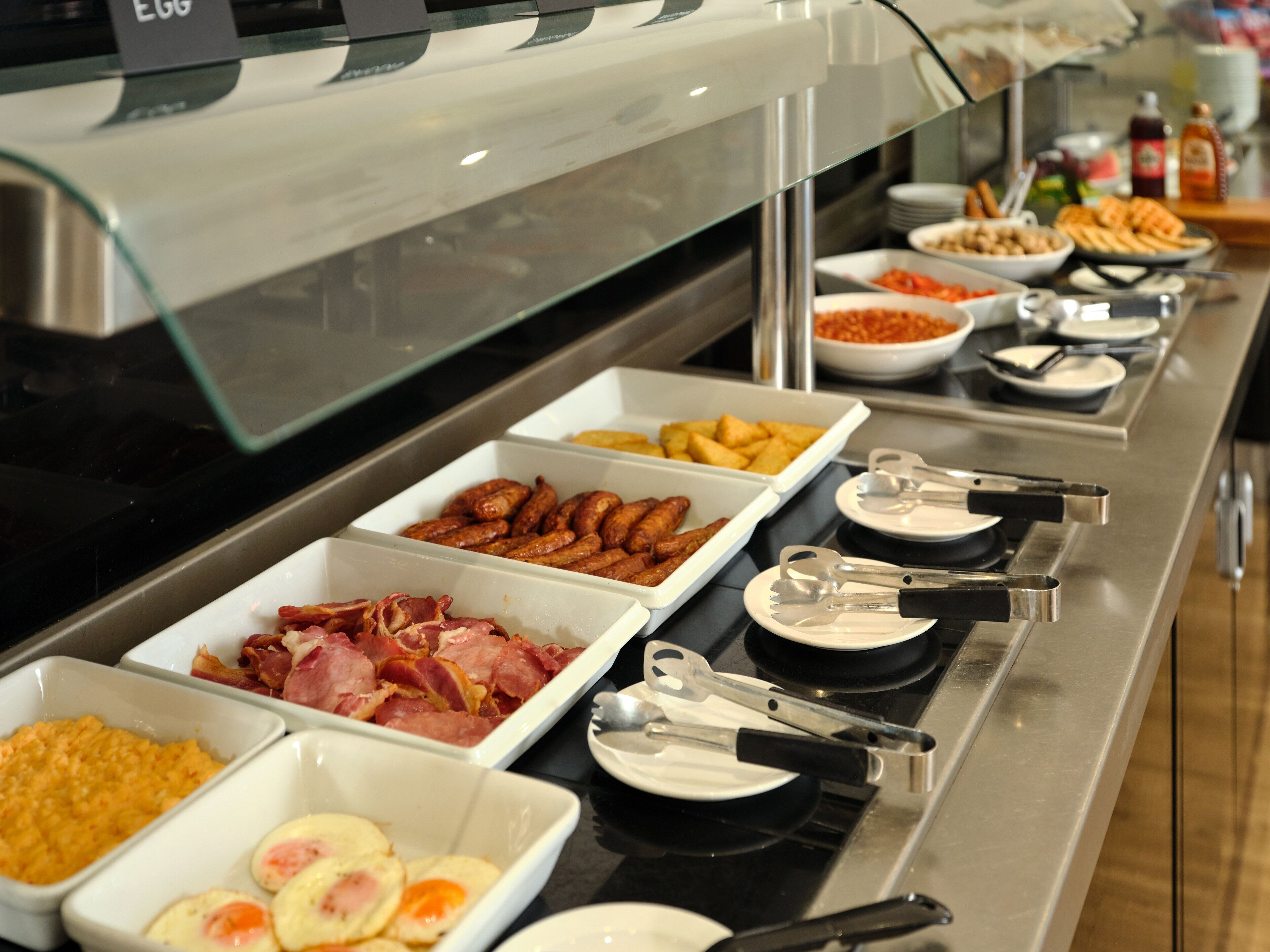 Buffet com diversos alimentos, incluindo carnes, ovos e vegetais.