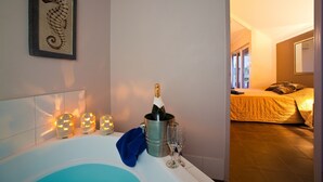 Un dormitorio con cama, mesita de noche y una mesita auxiliar con una botella de champán y dos copas.
