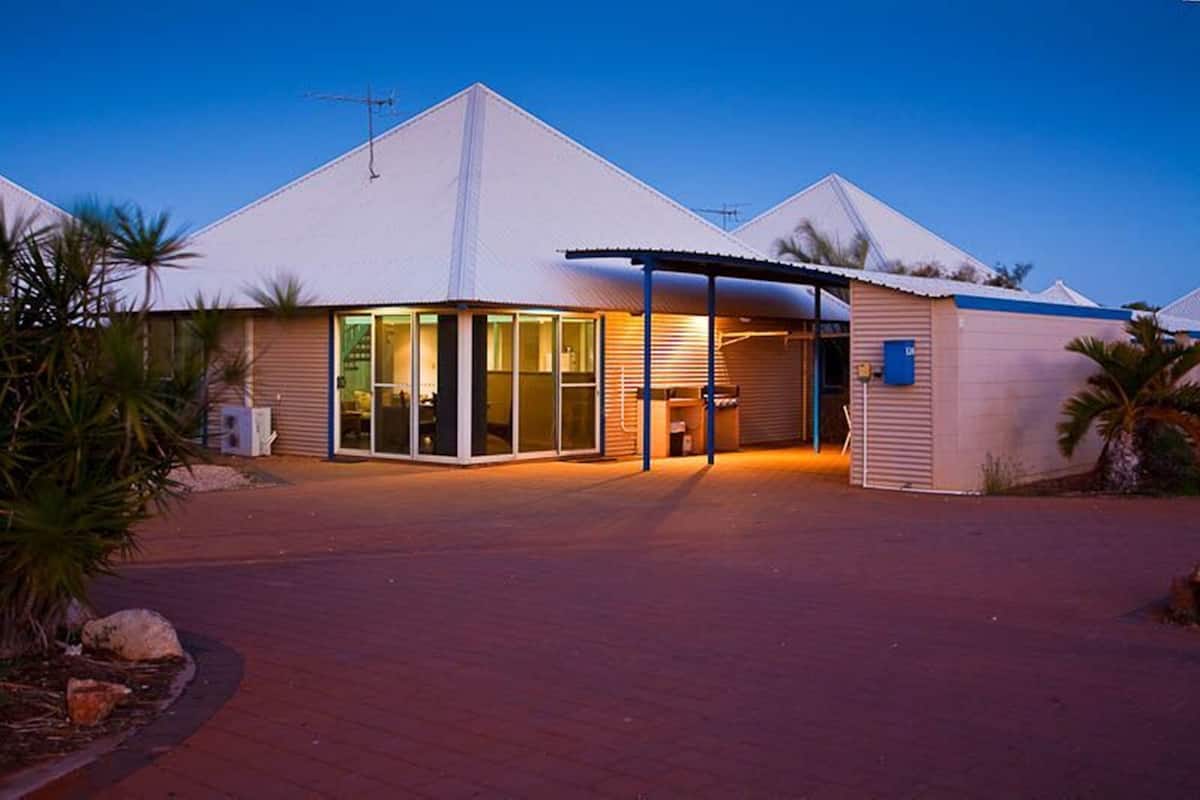 Un bâtiment moderne doté d’un toit plat, de grandes fenêtres et d’une entrée abritée.