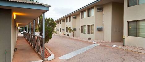 A row of motel rooms with a covered walkway and a gravel driveway.