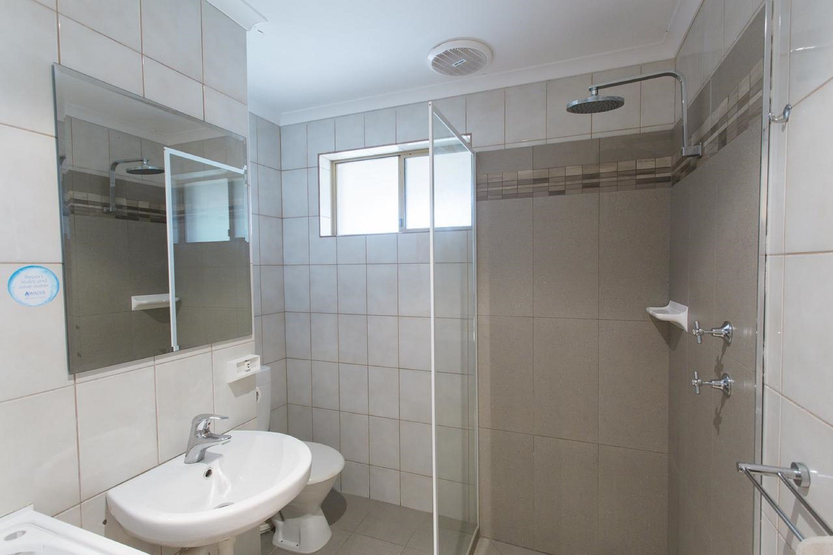 Een badkamer met een douchecabine van glas, een wastafel en een toilet.