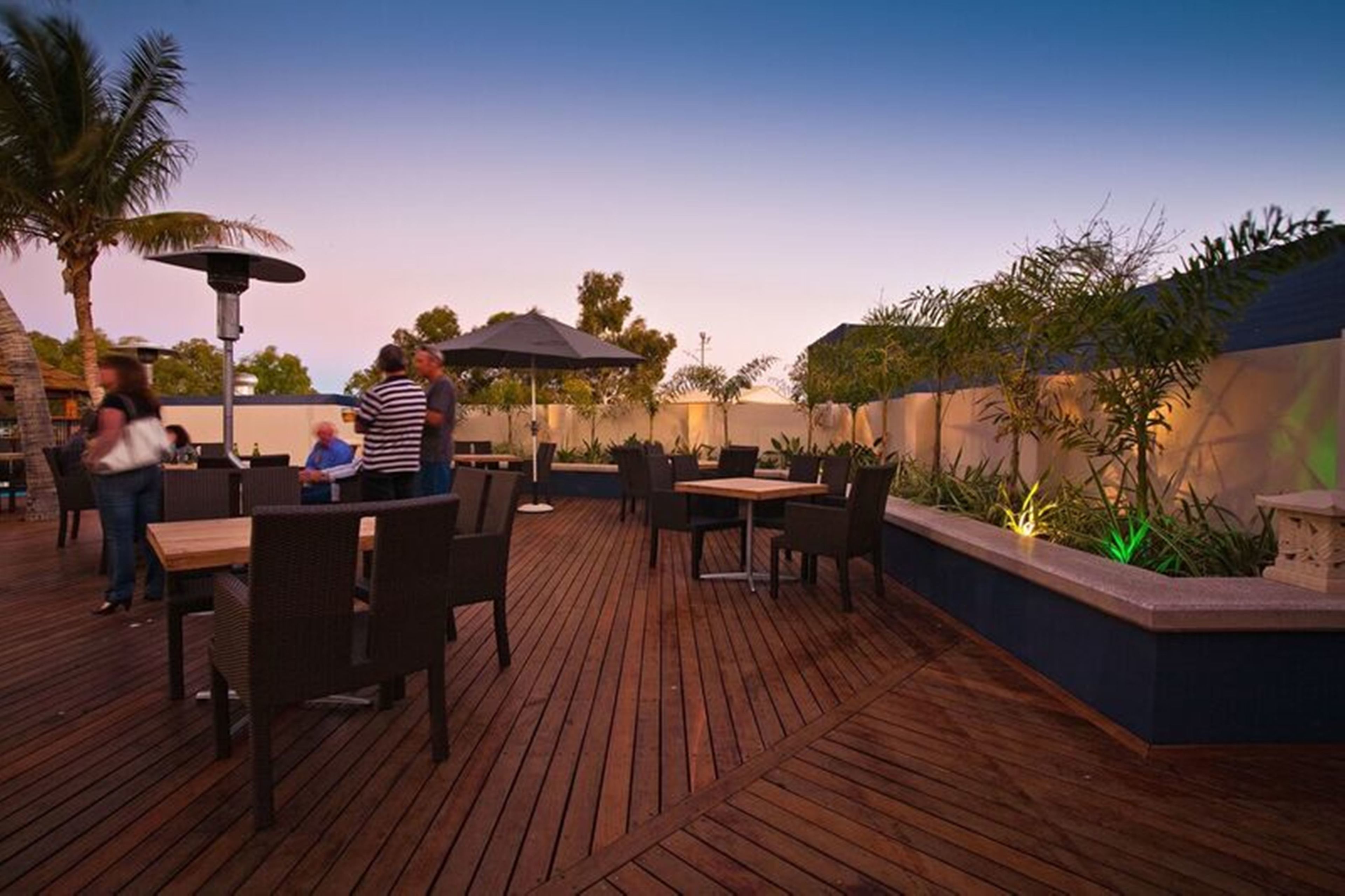 Eine Terrasse im Freien mit Holzboden, Tischen und Stühlen.