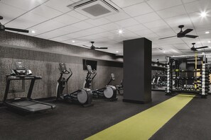 Ein Fitnessstudio mit Laufbändern, Crosstrainern und einem Gewichtecke.