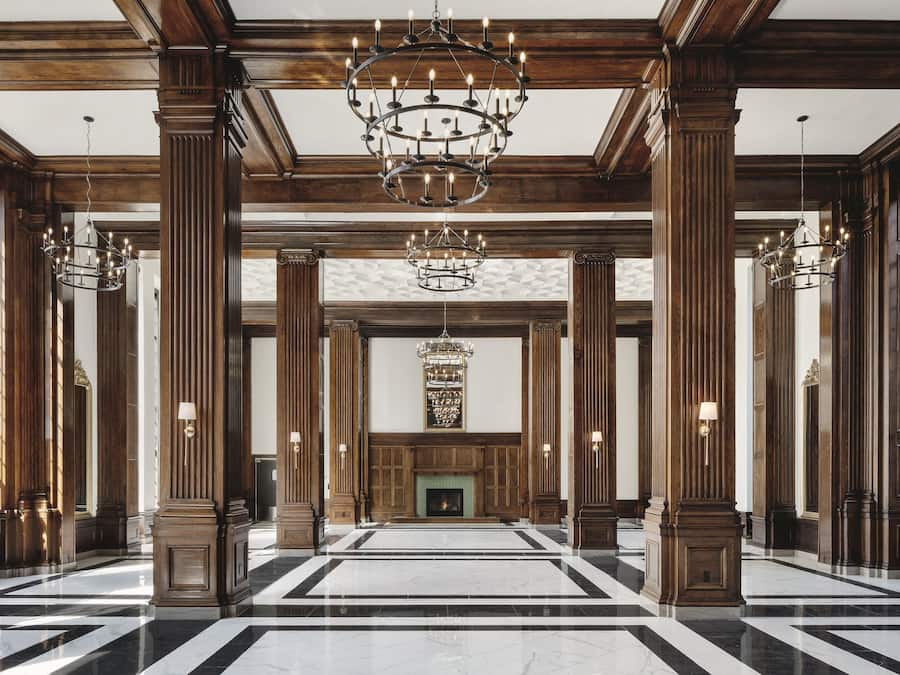 Eine prächtige Lobby mit hohen Holzsäulen, einem großen Chandelier und einem Kamin.