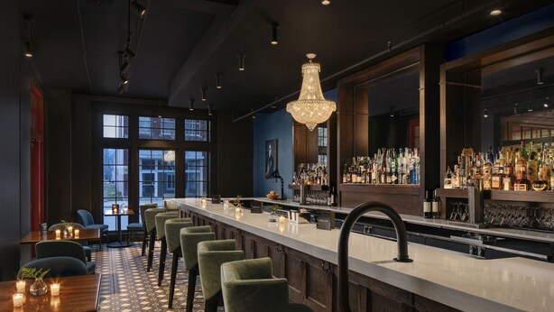 Una zona de bar con una barra larga, varios taburetes y un candelabro.
