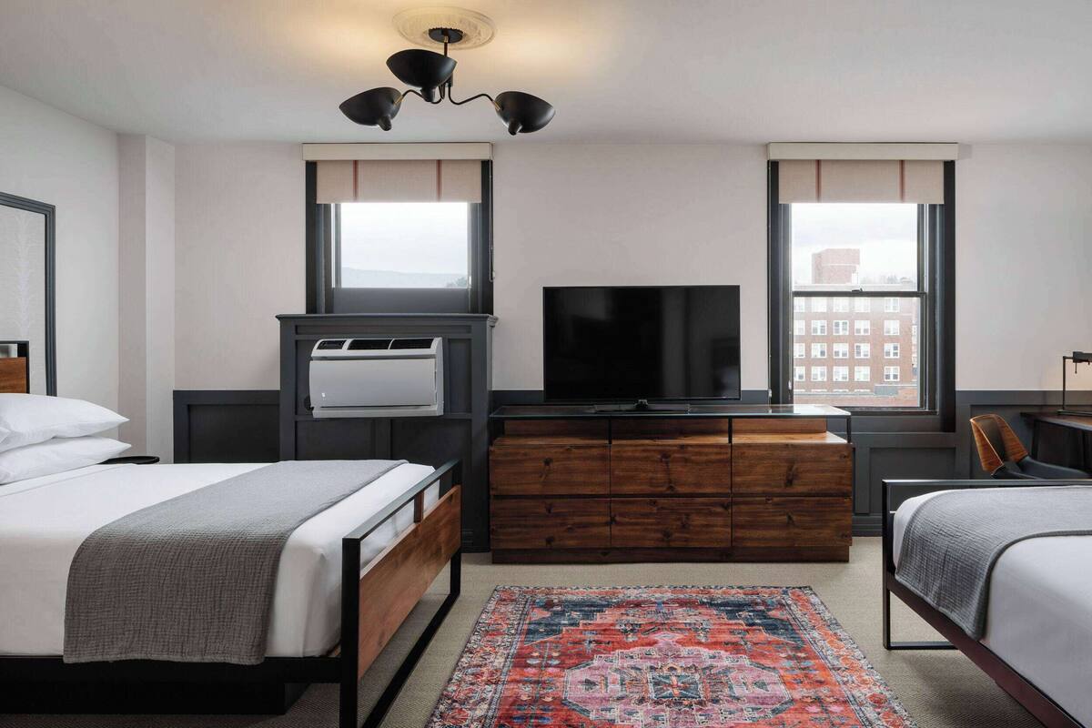 Een hotelkamer met een bed, een televisie, een kaptafel en een raam.