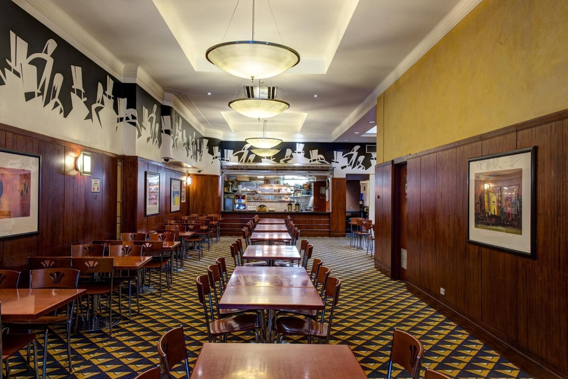 A restaurant with multiple tables and chairs, a patterned floor, and wall art.