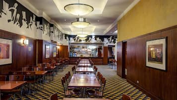 A restaurant with multiple tables and chairs, a patterned floor, and wall art.