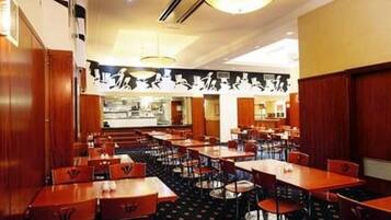 A restaurant with multiple tables and chairs, wooden paneling on the walls, and a central counter area.