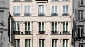 Un hotel de varios pisos con un estilo arquitectónico europeo clásico, que presenta balcones simétricos y una entrada central con puerta de cristal.