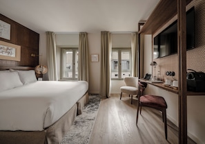 A hotel room with a large bed, a desk with a chair, a television, and a window with curtains. - Hotel Pulitzer Paris (Paris)