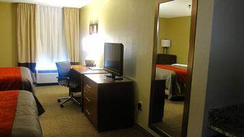 Habitación de hotel con dos camas, un escritorio, televisor, una silla y un espejo.