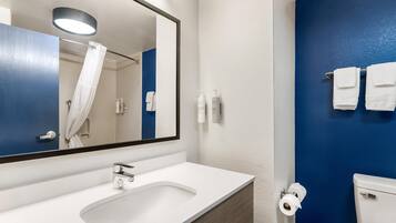 Une salle de bain avec un lavabo blanc, un miroir, un mur bleu et des toilettes.