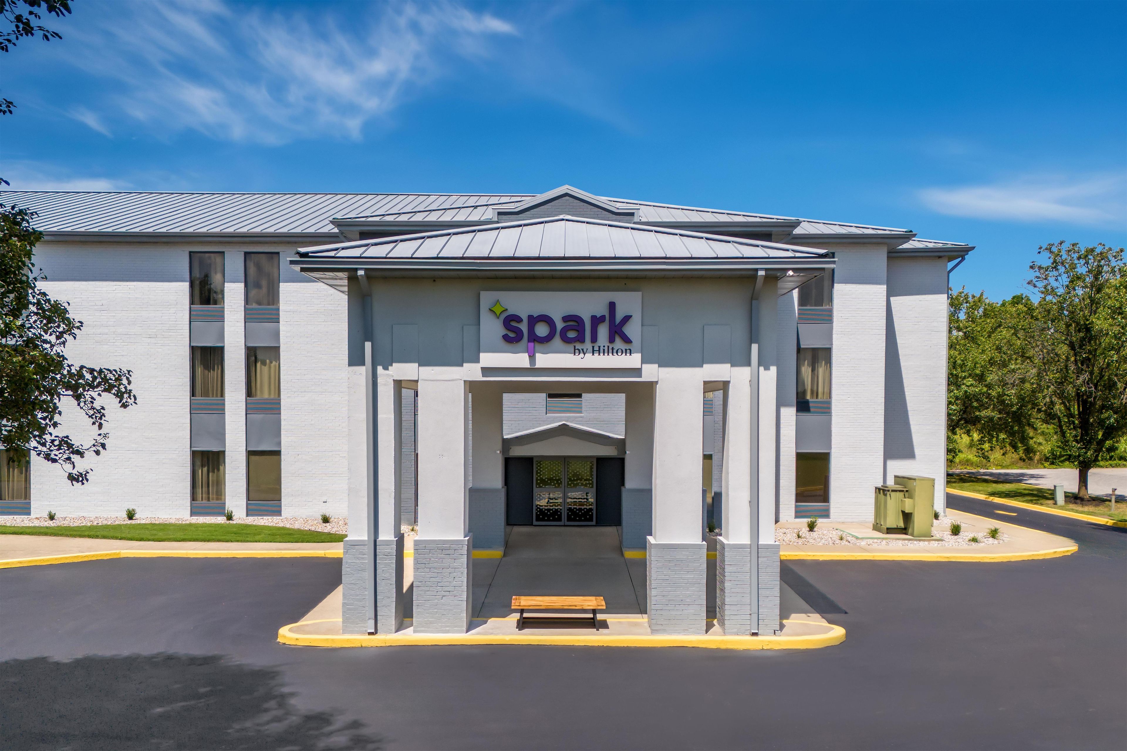 A hotel entrance with a sign reading 'spark by Hilton' and a bench outside.