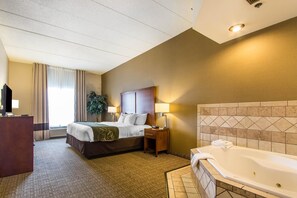 Ein Hotelzimmer mit Bett, Nachttisch, Lampe und Badewanne.