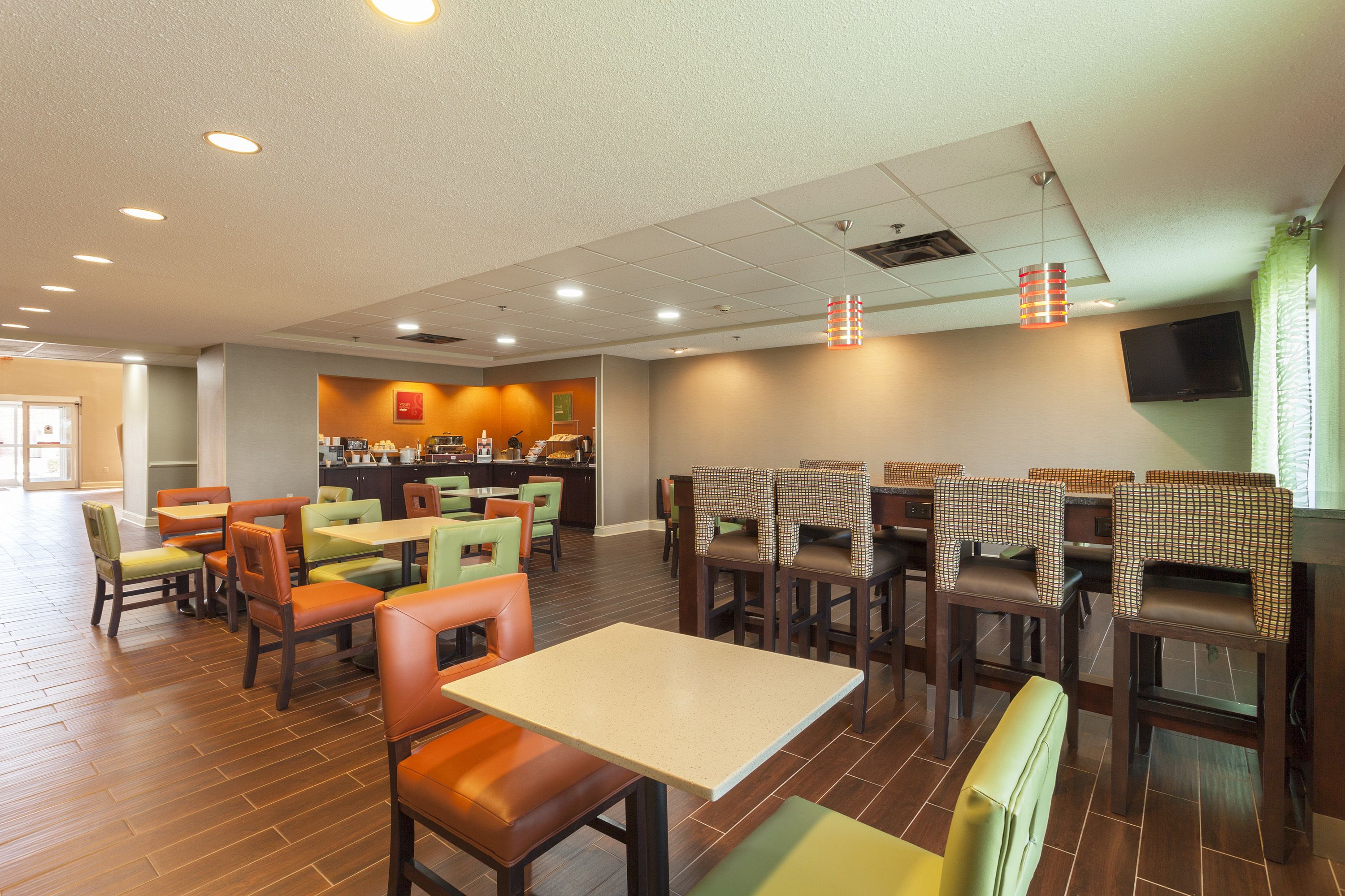 Un restaurante con suelo de madera, varias zonas de estar, incluyendo cabinas y mesas, y una cocina al fondo.