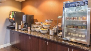 Una kitchenette con refrigerador, cafetera y exhibición de yogur.