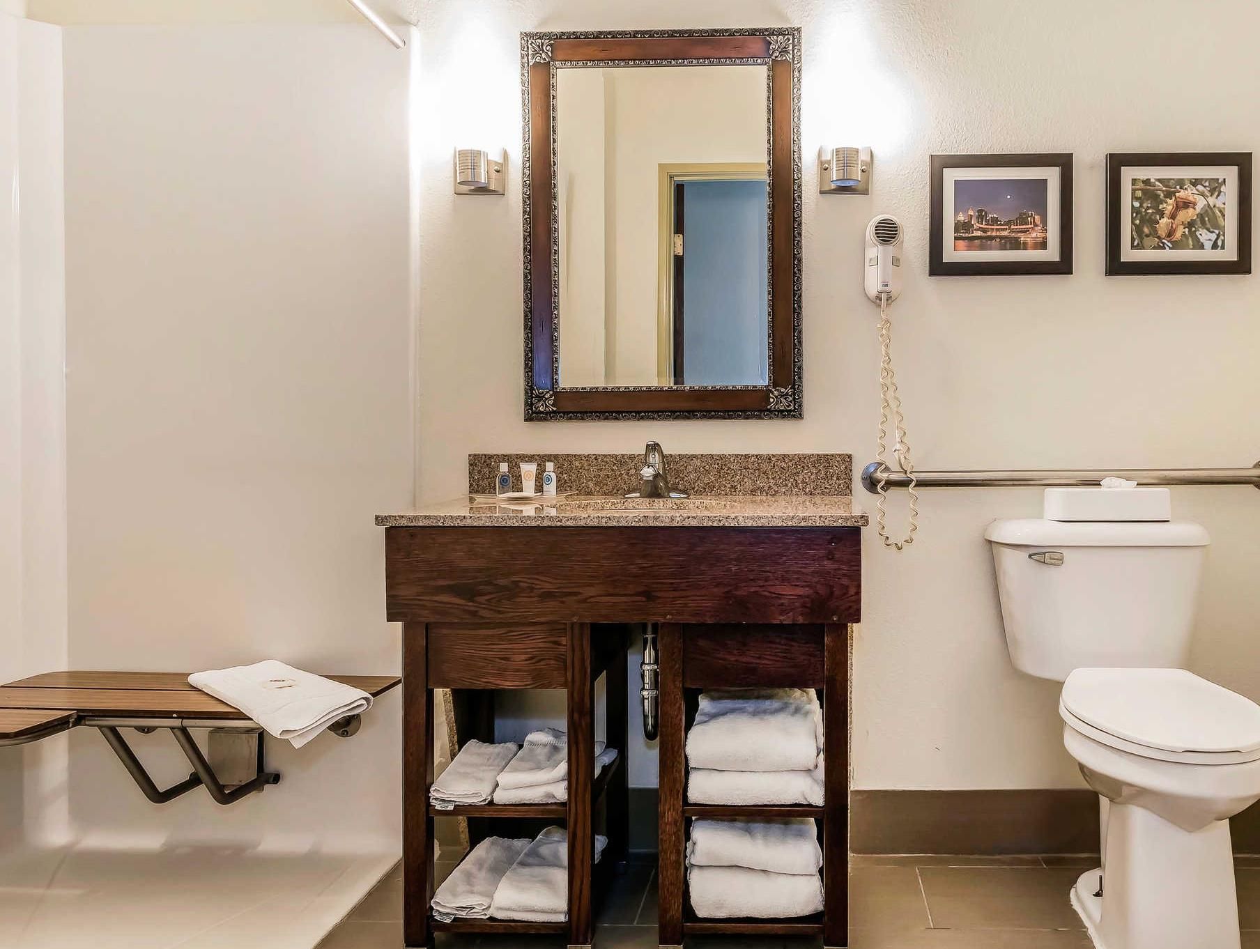A bathroom with a wooden vanity, a toilet, a mirror, and a towel rack.