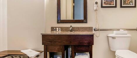 A bathroom with a wooden vanity, a toilet, a mirror, and a towel rack.
