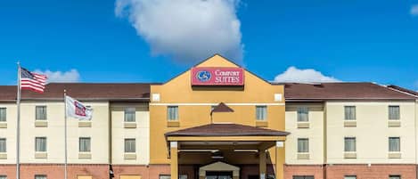 A hotel with a sign reading 'Comfort Suites' and a flagpole with an American flag.