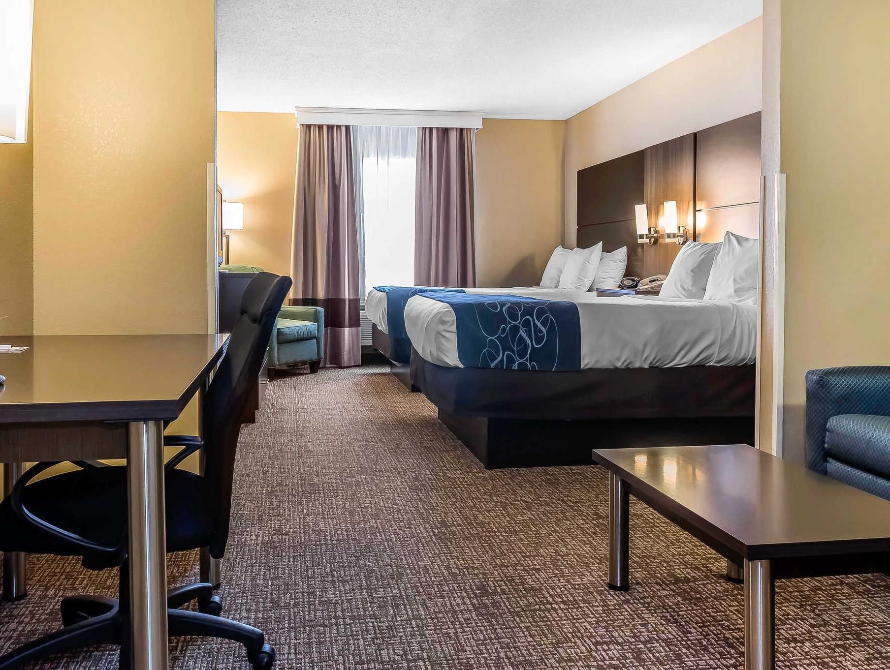 Una habitación de hotel con una cama, un escritorio, una silla y una pequeña mesa.