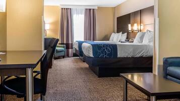 Una habitación de hotel con una cama, un escritorio, una silla y una pequeña mesa.