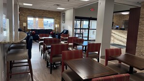 A restaurant with booths and tables, a stone wall, and a view of the outside. - Comfort Suites Miamisburg - Dayton South (Miamisburg)