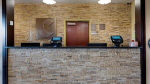 A reception desk with two ATMs, a wooden door, and a stone wall. - Comfort Suites Miamisburg - Dayton South (Miamisburg)