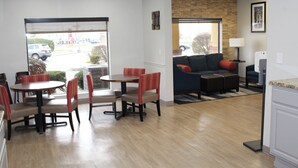 A hotel lobby with a dining area, a sofa, and a kitchen area. - Comfort Suites Miamisburg - Dayton South (Miamisburg)