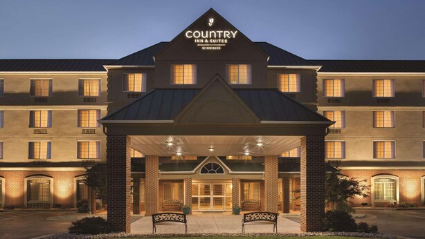 A large, multi-story hotel with a prominent entrance and a covered area with benches. - Country Inn & Suites by Radisson, Lexington, VA (Lexington)