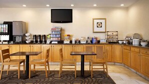 A hotel kitchen with wooden cabinets, a flat-screen TV, a coffee station, and a buffet area. - Country Inn & Suites by Radisson, Lexington, VA (Lexington)