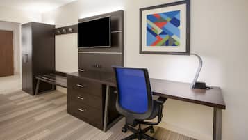 A modern office space with a desk, chair, and a large flat-screen TV mounted on the wall.