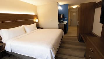 Hotellihuone, jossa on suuri sänky, yöpöydät, työpöytä tuolilla, televisio ja vaatekaappi.