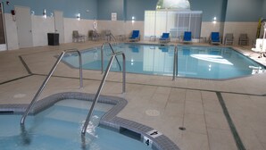 An indoor swimming pool with clear water, a lifeguard chair, and a clock on the wall. - Holiday Inn Express and Suites Manassas by IHG (Manassas)