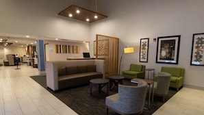 A lobby with a sofa, chairs, a desk, and a reception area. - Holiday Inn Express and Suites Manassas by IHG (Manassas)