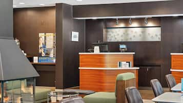 A hotel lobby with a reception desk, seating area, and a fireplace.