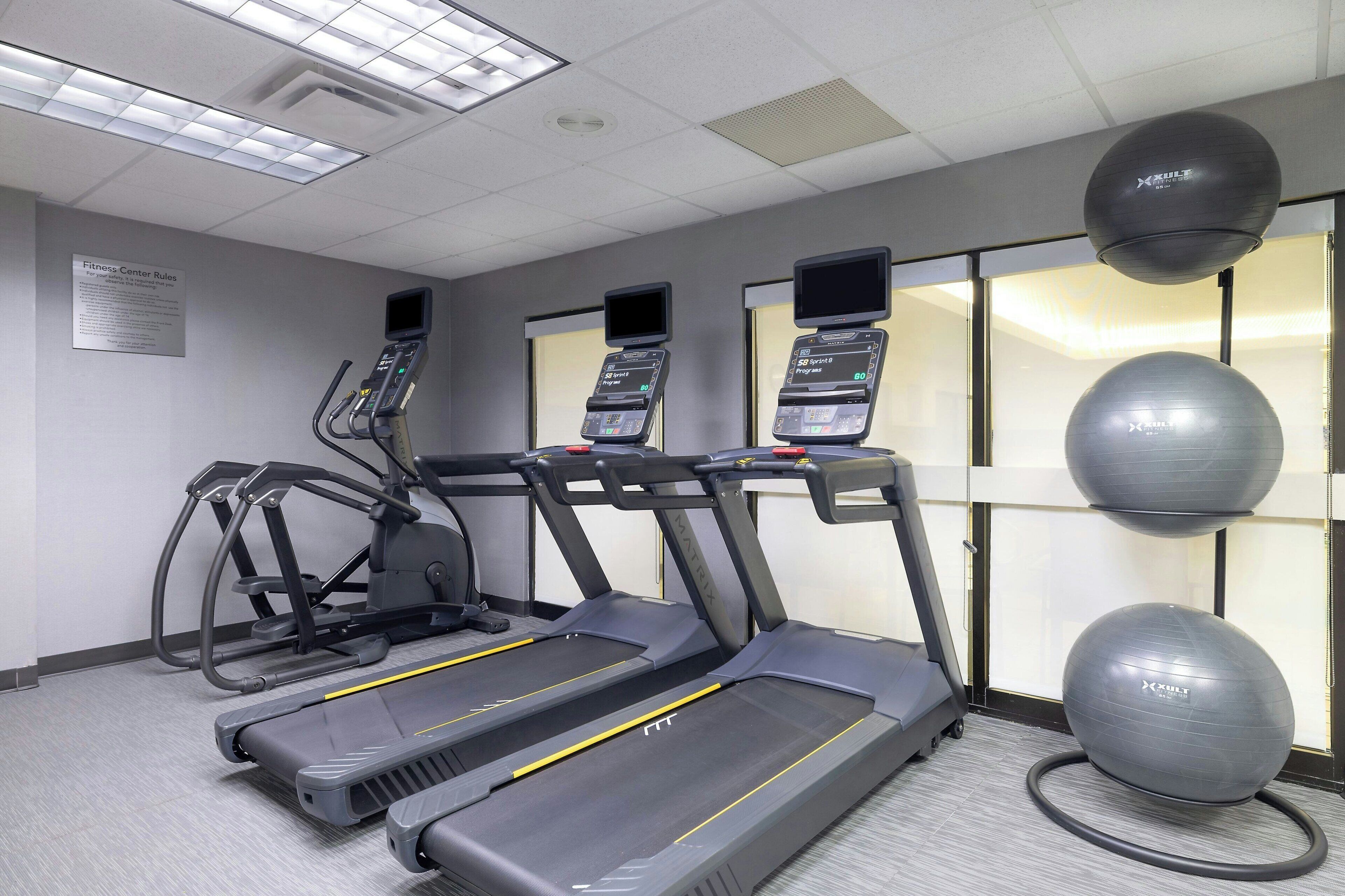 A fitness center with treadmills, elliptical machines, and exercise balls.