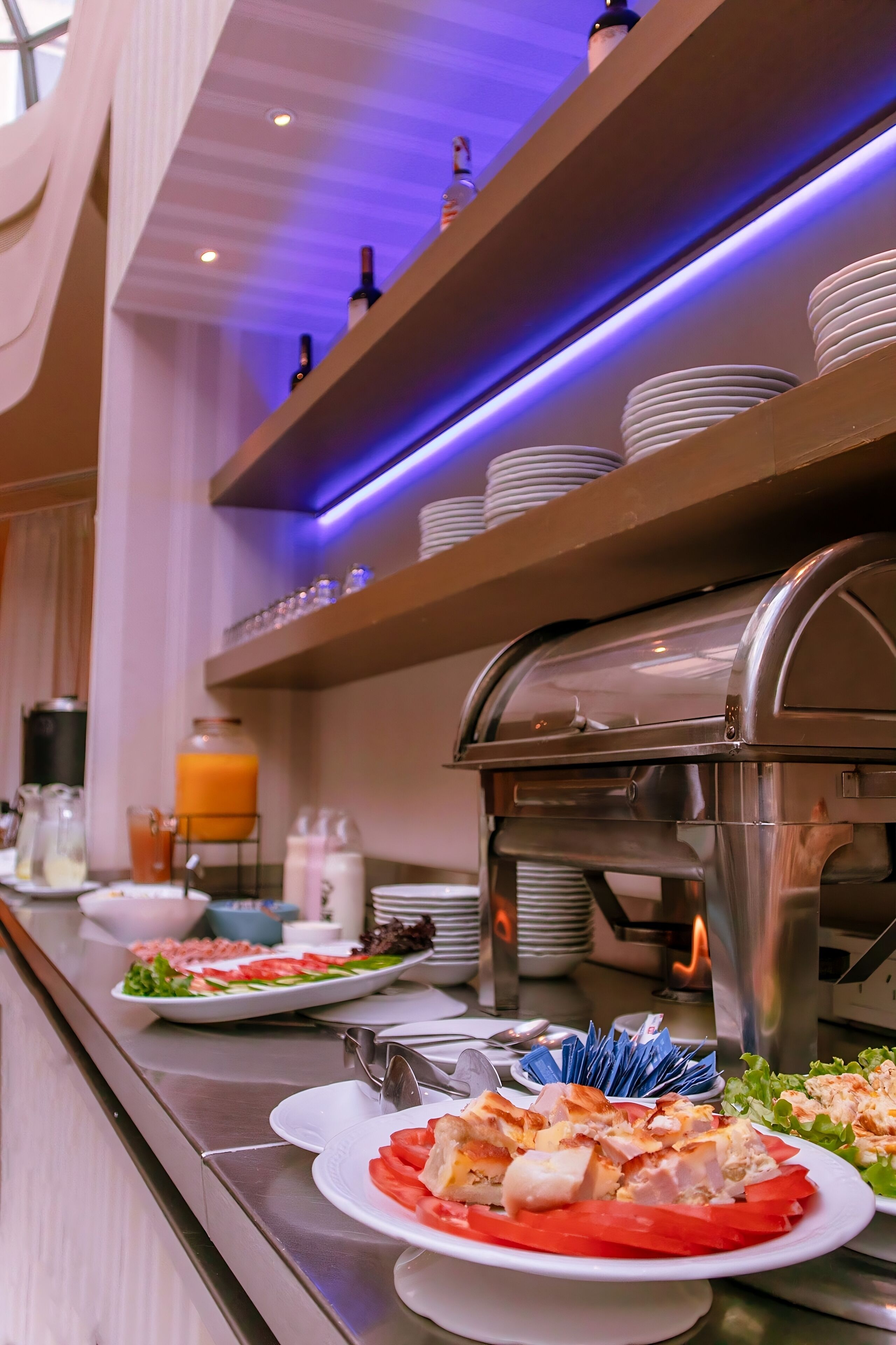 A buffet setup with various food items, a coffee machine, and a juice dispenser.
