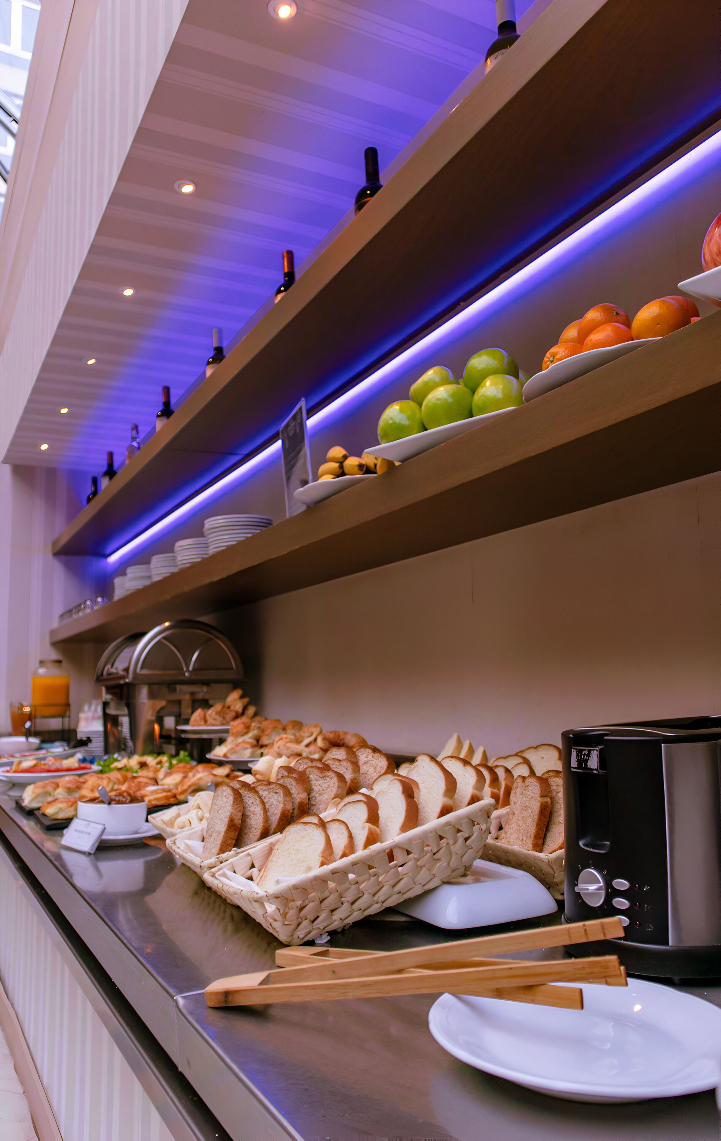Un bufé con diversos alimentos, como pan, frutas y un tostador.