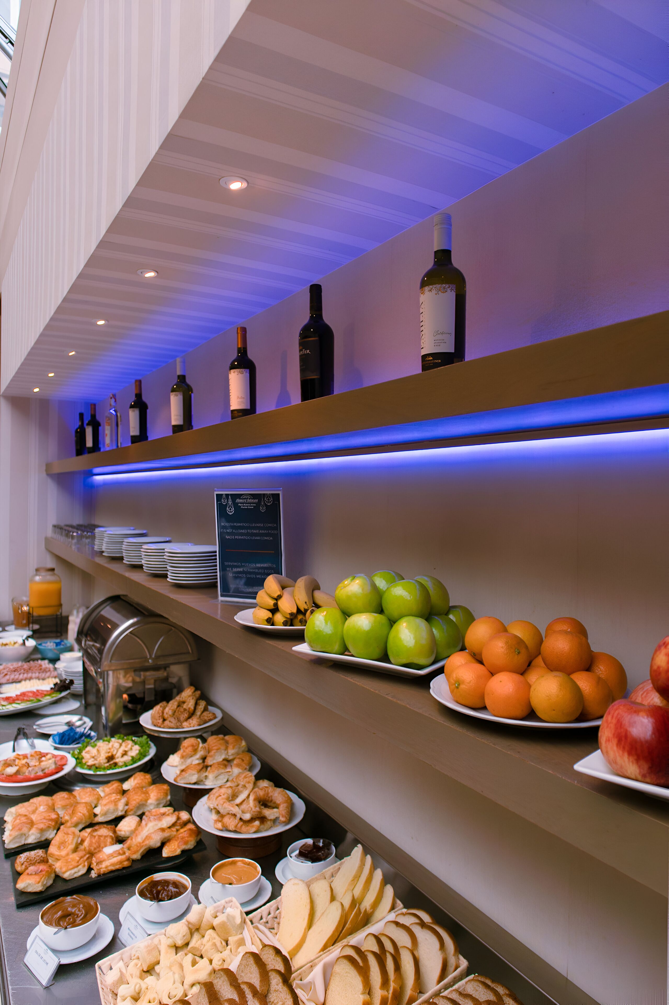 A buffet with various food items, including fruits, pastries, and beverages.