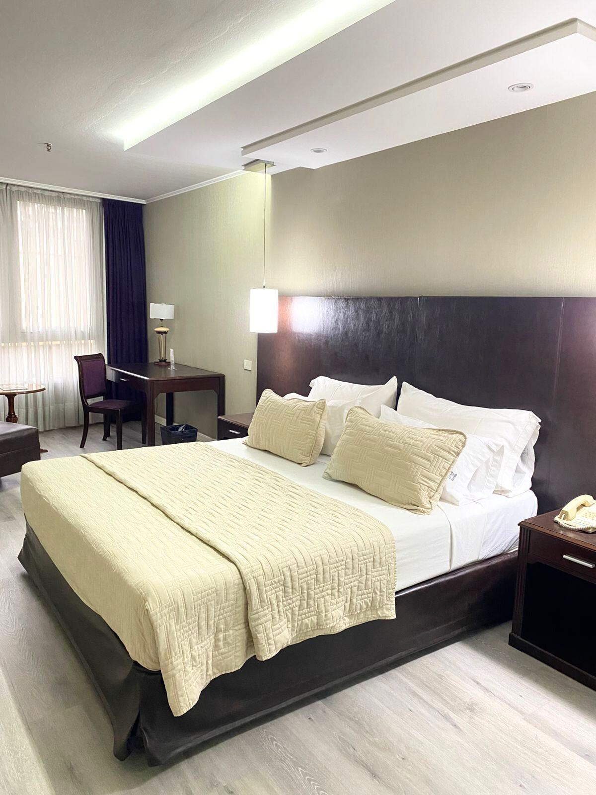 A hotel room with a large bed, bedside tables, a desk, and a chair.