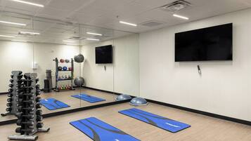 A gym with exercise mats, a weight rack, and a mirror.