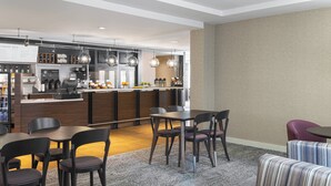 A modern hotel lobby with a bar area, seating arrangements, and a carpeted floor. - Courtyard by Marriott Charlottesville - University Medical Center (Charlottesville)