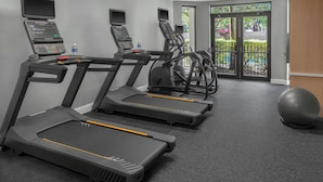 Un gimnasio con cintas de correr, una bicicleta estática y una pelota de ejercicios.