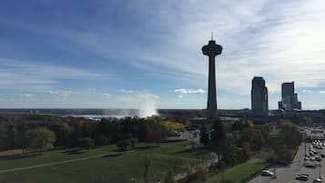 Une tour surmontée d’une flèche, entourée d’un parking et d’une zone verdoyante avec des arbres.