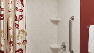 A bathroom with a bathtub, a shower, and a handrail.