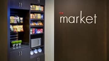 A snack display with various chips and snacks, a small plant, and a wall with the text "the market".